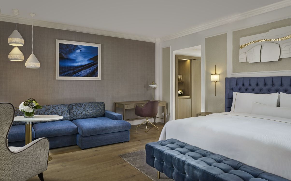 Large suite bedroom with blue furniture and artwork in The College Green Hotel Dublin