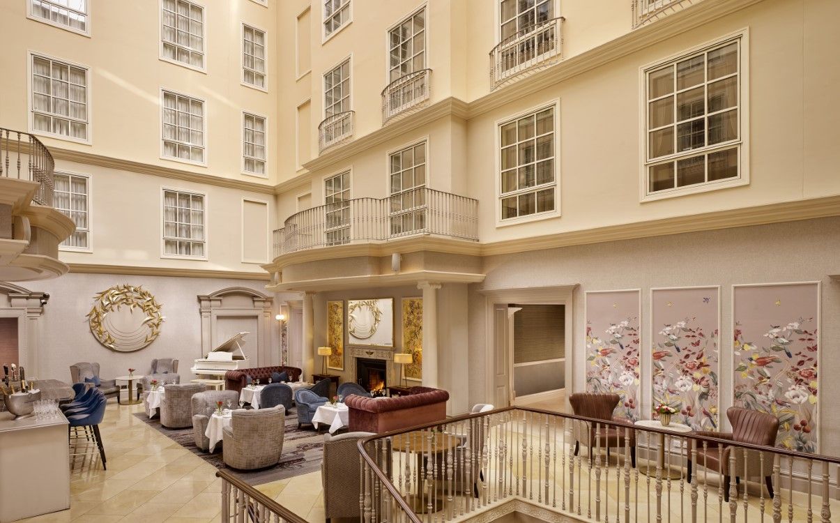 Wide angle of Atrium Lounge with tables and chairs set next to fire