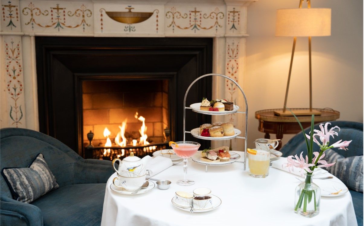 Table next to fire with Afternoon Tea tiered set up, cocktails and tea