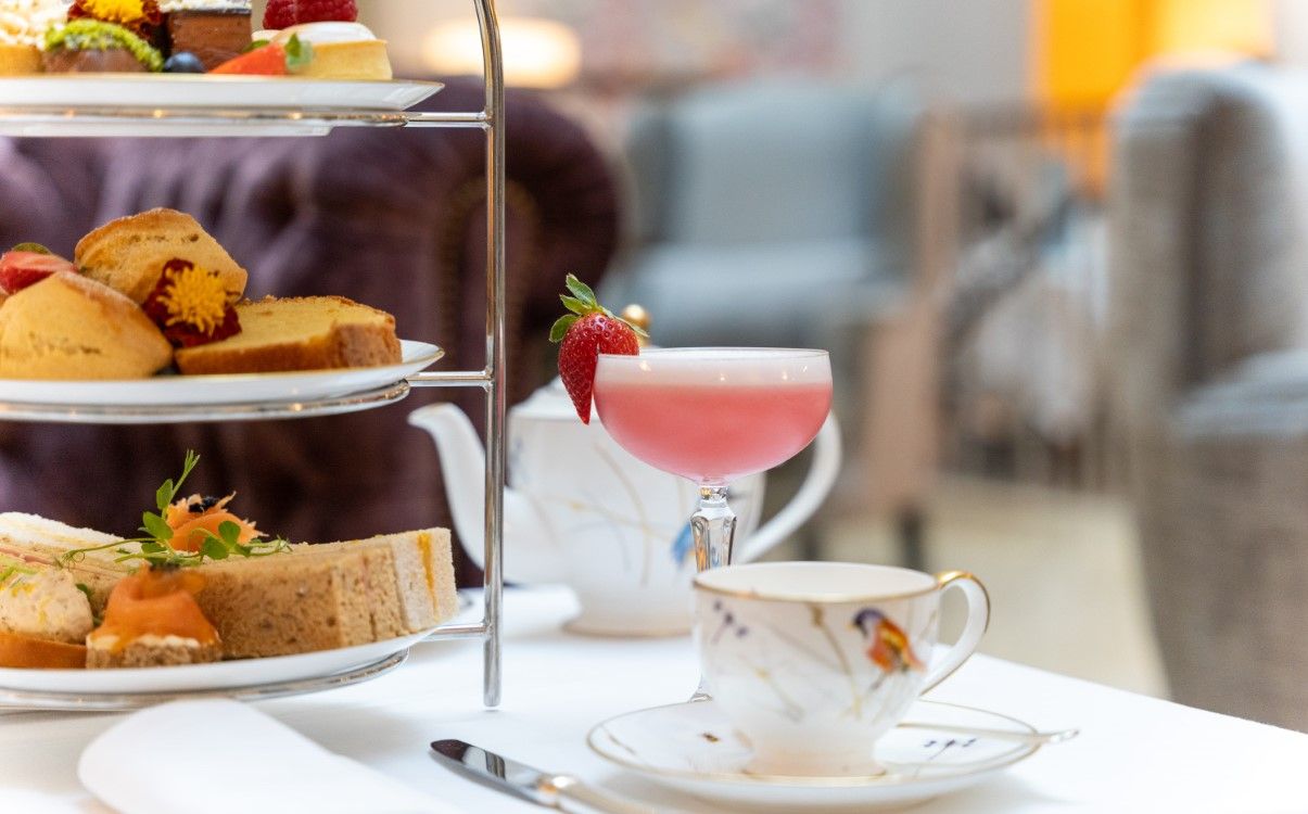 Pink cocktail with tea cup and Afternoon Tea tiered set up in The College Green Hotel Dublin