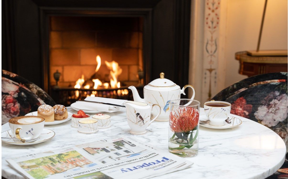 Tea crockery and newspaper set on table next to fire