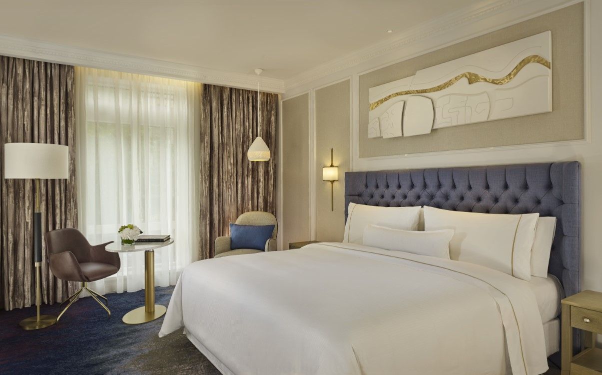 Large deluxe king room with blue headboard and closed curtains